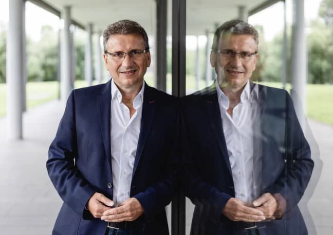 Ein Mann mit Brille schaut lächelnd in die Kamera.