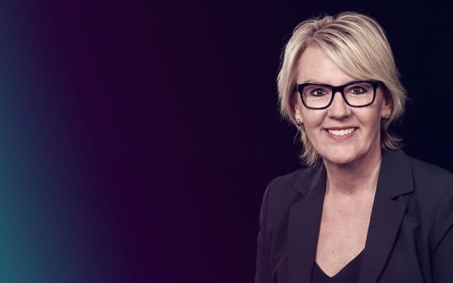Nahaufnahme von einer Trainerin. Sie trägt eine Brille und lächelt in die Kamera.