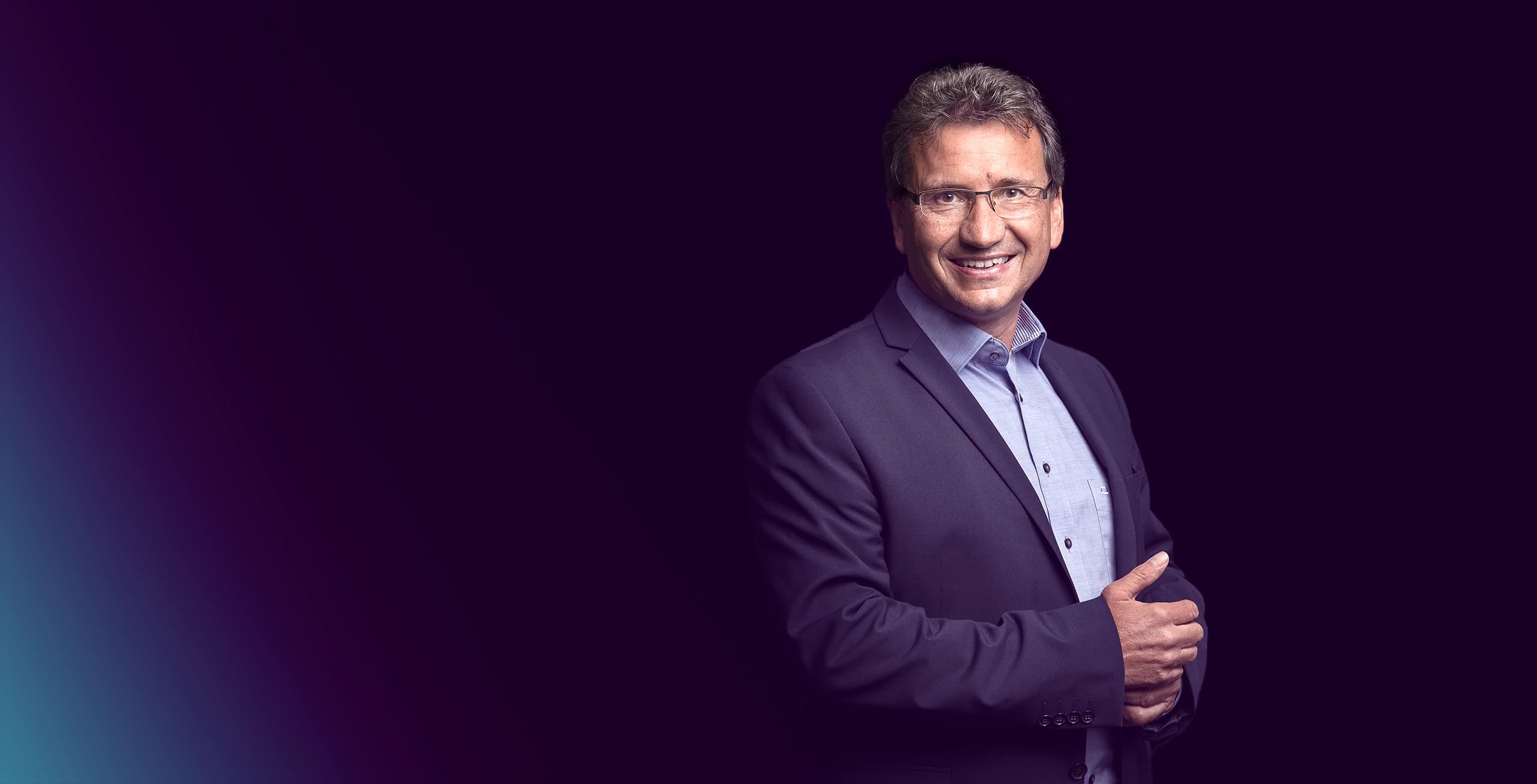 Ein Mann mit Brille schaut lächelnd in die Kamera.