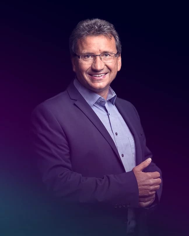 Ein Mann mit Brille schaut lächelnd in die Kamera.