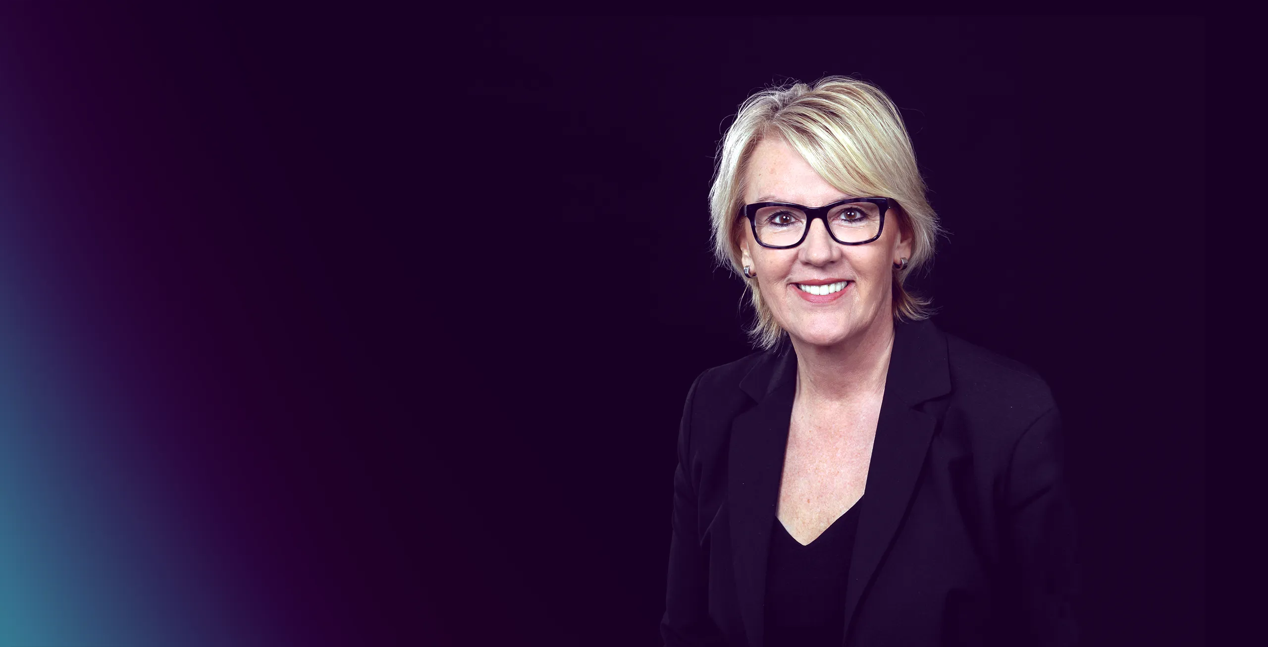 Eine Nahaufnahme von einer Unternehmerin mit Brille. Sie lächelt in die Kamera.